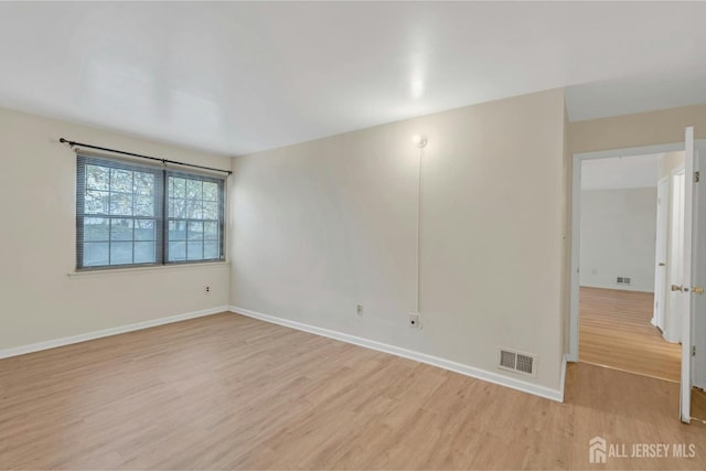 unfurnished room featuring light wood-style floors, visible vents, and baseboards