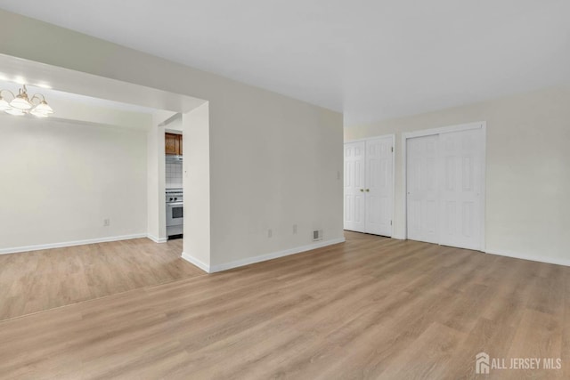 spare room with visible vents, baseboards, an inviting chandelier, and light wood finished floors