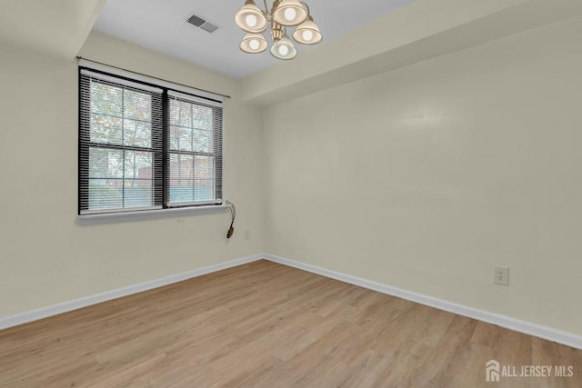 unfurnished room featuring a chandelier, visible vents, light wood-style flooring, and baseboards