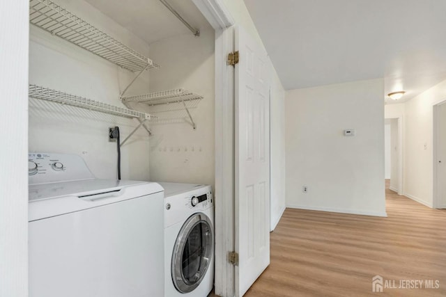 laundry room with washer and dryer, baseboards, light wood-style floors, and laundry area