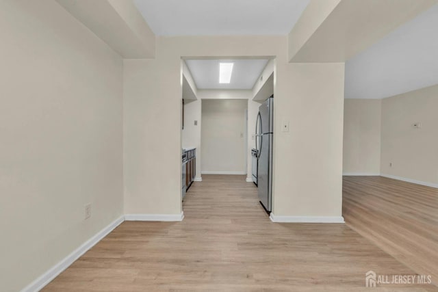 hall with baseboards and light wood finished floors