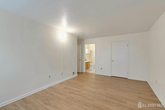 unfurnished bedroom with visible vents, ensuite bathroom, light wood-type flooring, and baseboards