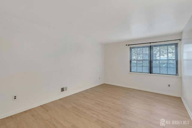 unfurnished room featuring light wood-style flooring, baseboards, and visible vents