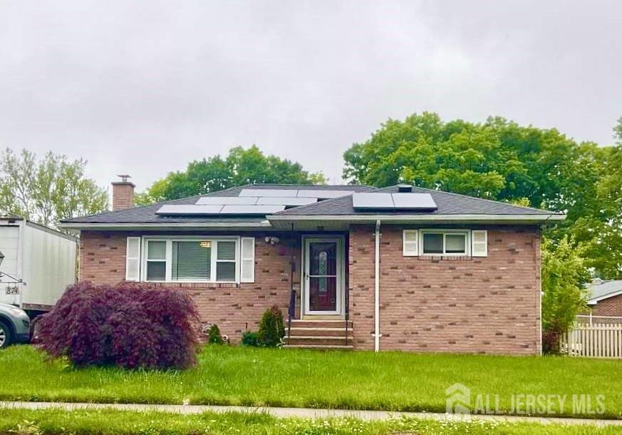 view of front of house with a front lawn and solar panels