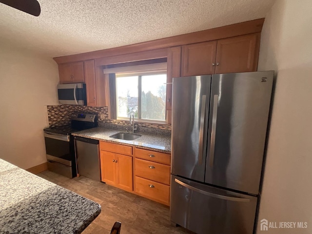 kitchen featuring tasteful backsplash, appliances with stainless steel finishes, sink, and a textured ceiling