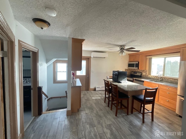 dining space featuring hardwood / wood-style floors, sink, a baseboard heating unit, and a wall mounted AC