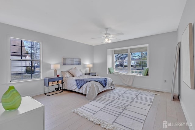 bedroom with light wood-style floors, ceiling fan, and baseboards