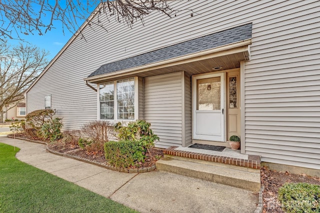 view of exterior entry with a shingled roof