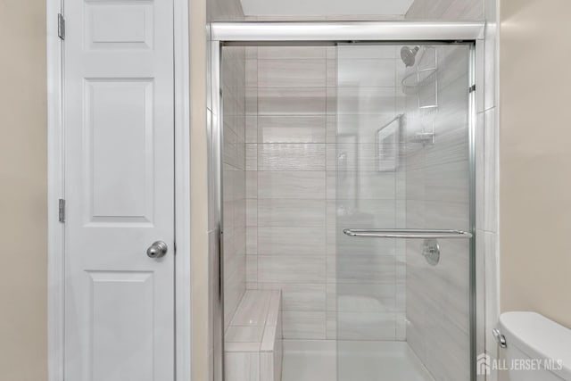 full bathroom featuring toilet and a stall shower