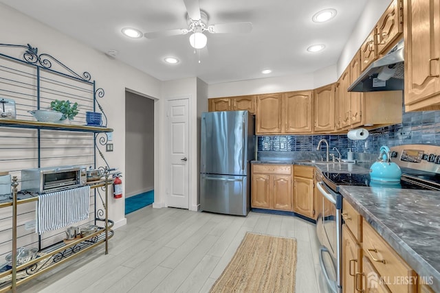 kitchen with stainless steel appliances, tasteful backsplash, a sink, and under cabinet range hood