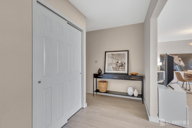 hall with baseboards and light wood finished floors