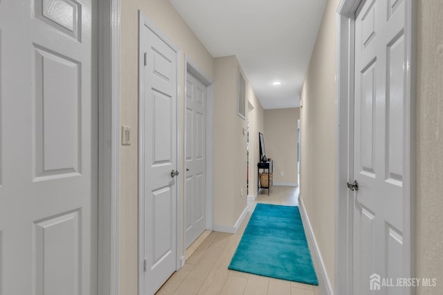 hall with light wood-type flooring and baseboards