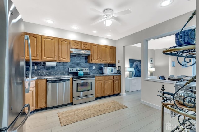 kitchen featuring decorative backsplash, brown cabinetry, light wood-style flooring, appliances with stainless steel finishes, and under cabinet range hood