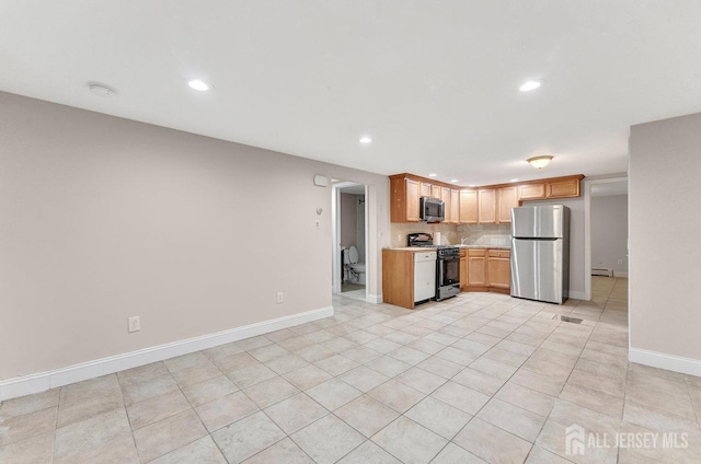 kitchen with baseboard heating, appliances with stainless steel finishes, light tile patterned flooring, and backsplash