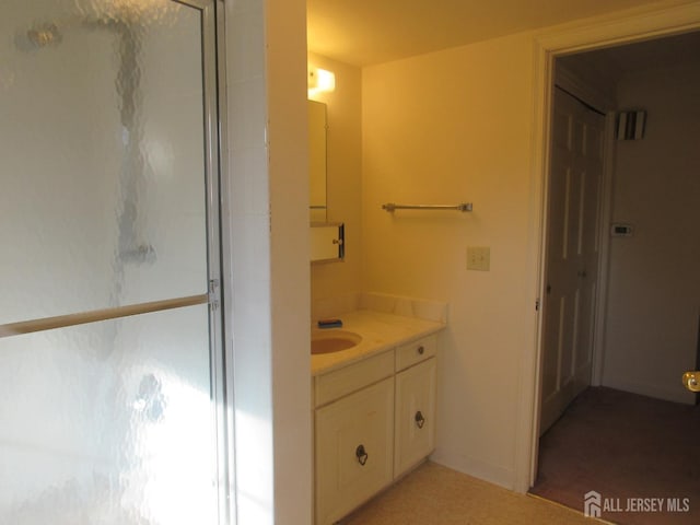 bathroom featuring a shower with shower door and vanity