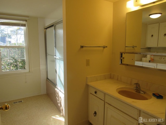 full bathroom with visible vents, vanity, and bath / shower combo with glass door