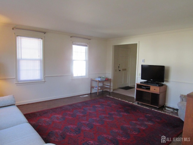 living area with crown molding, baseboards, and wood finished floors