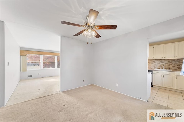 empty room featuring ceiling fan, light carpet, and sink