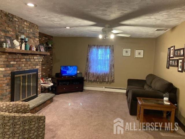 living area featuring a ceiling fan, carpet flooring, a brick fireplace, and a baseboard heating unit