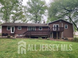 back of house featuring a deck, a lawn, and a chimney