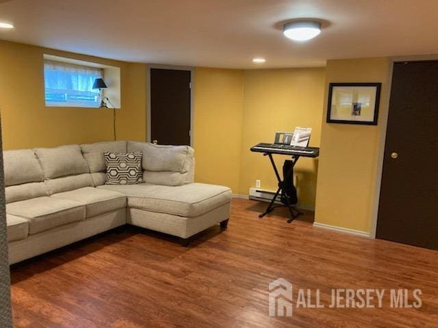 living room featuring wood finished floors, a baseboard heating unit, and baseboards