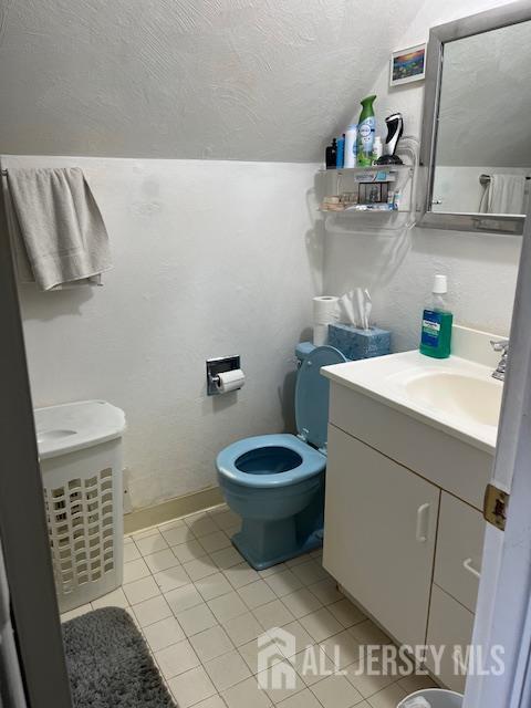12 Landry Rd, Franklin, NJ 08873 - bathroom featuring a textured ceiling, vanity, toilet, lofted ceiling, and tile patterned flooring