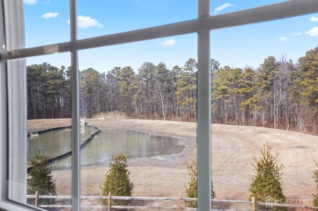 property view of water featuring a forest view and fence