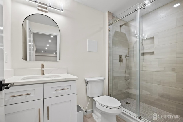 bathroom with baseboards, a shower stall, toilet, and vanity