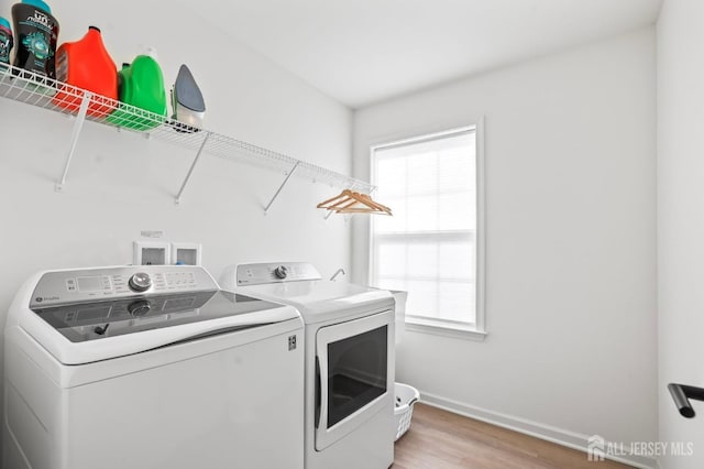 laundry area featuring baseboards, laundry area, wood finished floors, and washer and dryer