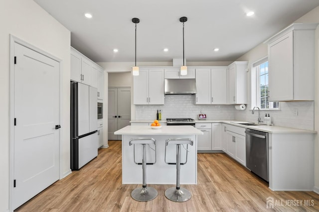 kitchen featuring white cabinets, a kitchen island, appliances with stainless steel finishes, light countertops, and under cabinet range hood