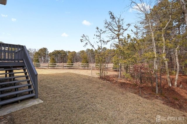 view of yard featuring a rural view, fence, and stairs