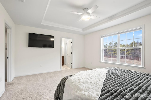 bedroom featuring ensuite bathroom, light colored carpet, a ceiling fan, baseboards, and a raised ceiling