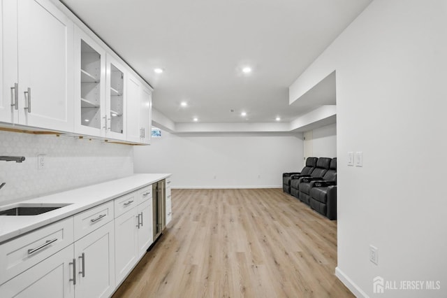 kitchen featuring light countertops, a sink, glass insert cabinets, and white cabinets