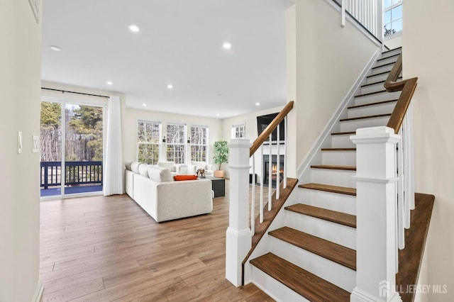 stairs with wood finished floors and recessed lighting