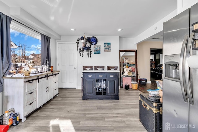 kitchen with white cabinetry, stainless steel fridge with ice dispenser, light hardwood / wood-style flooring, and blue cabinets