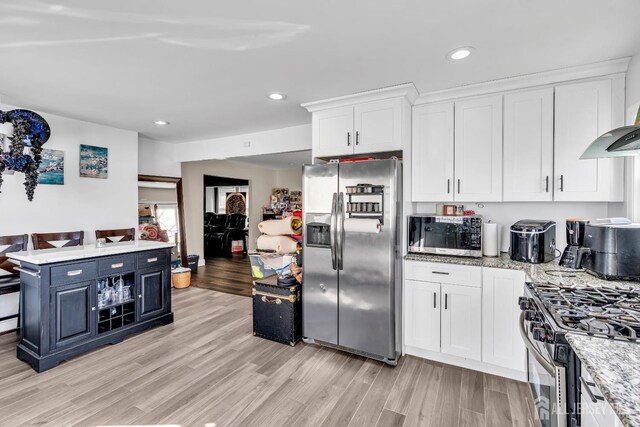 kitchen featuring extractor fan, white cabinetry, stainless steel appliances, light stone countertops, and light wood-type flooring