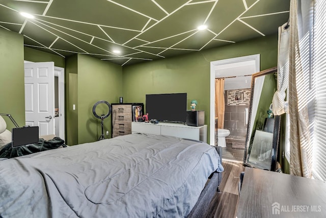 bedroom with hardwood / wood-style floors and ensuite bath