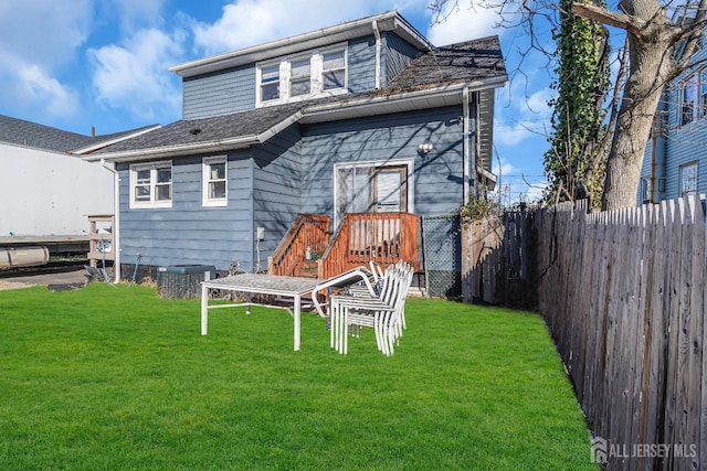 rear view of property featuring a yard and central air condition unit