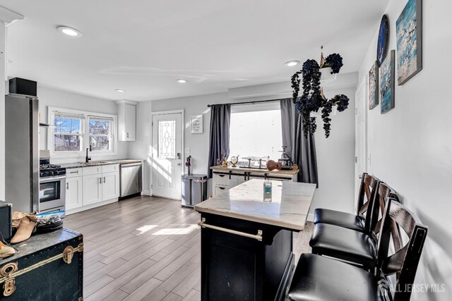 kitchen featuring a healthy amount of sunlight, stainless steel appliances, light wood-type flooring, and white cabinets