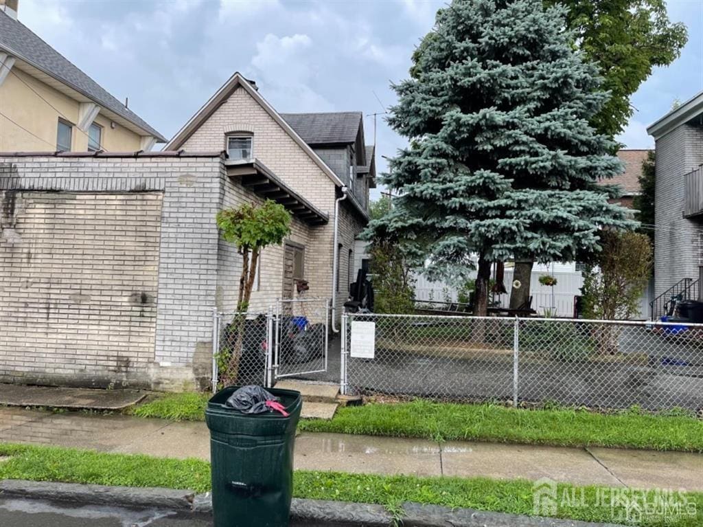 82 Pulaski Ave, Carteret, NJ 07008 - view of side of home featuring brick siding, a fenced front yard, and a gate