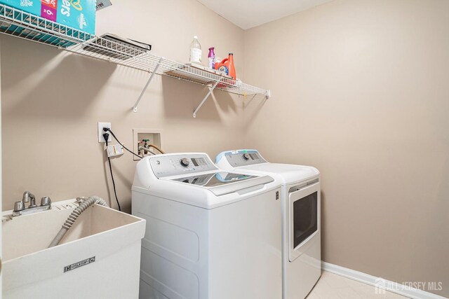 clothes washing area with independent washer and dryer and sink