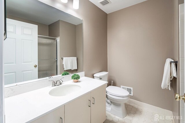 bathroom featuring tile patterned floors, vanity, an enclosed shower, and toilet