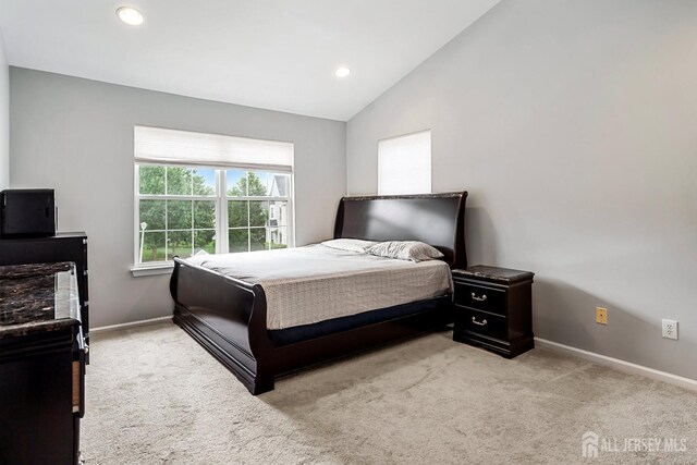 bedroom featuring light carpet and vaulted ceiling