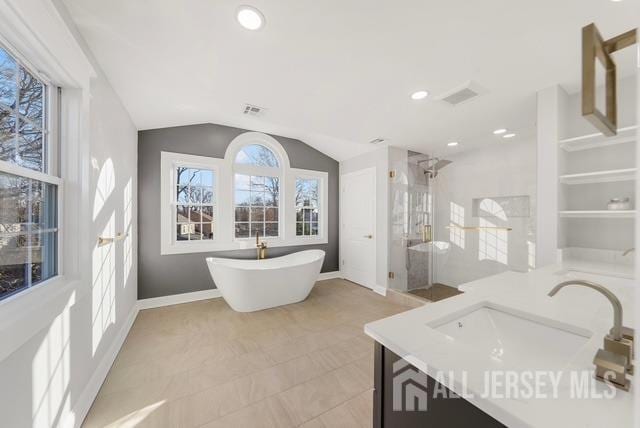 bathroom with a stall shower, visible vents, lofted ceiling, vanity, and a freestanding tub