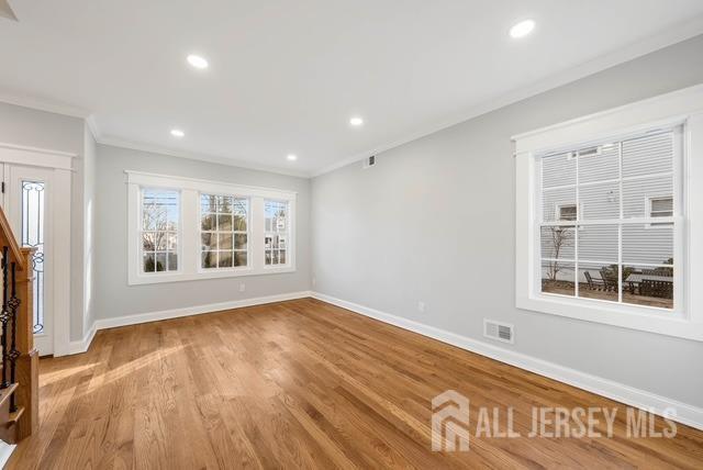 unfurnished living room featuring recessed lighting, crown molding, and baseboards