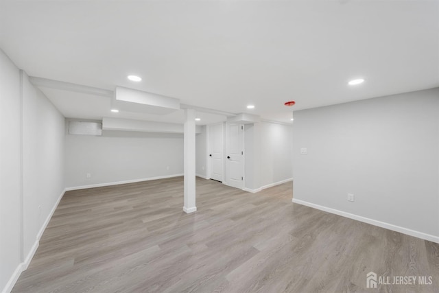 finished below grade area with light wood finished floors, baseboards, and recessed lighting