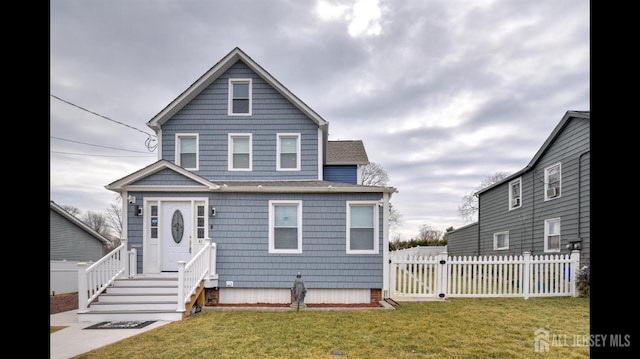 view of front of house featuring entry steps, fence, and a front lawn