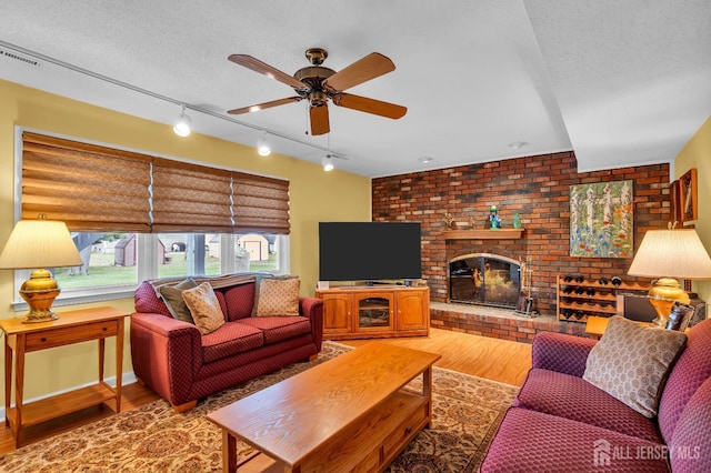 423 Brentwood Dr, Piscataway, NJ 08854 - living area with track lighting, wood finished floors, a ceiling fan, a fireplace, and a textured ceiling