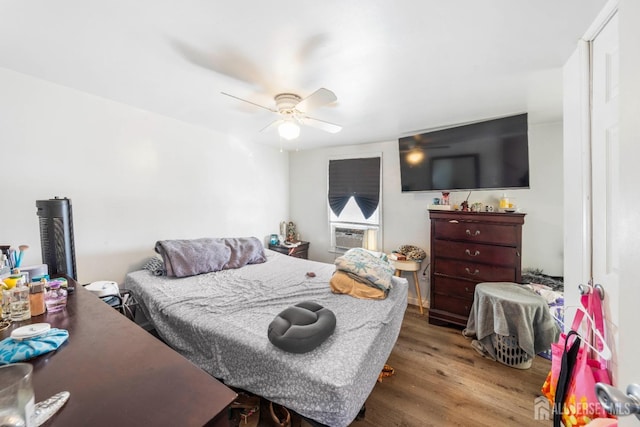 bedroom with cooling unit, ceiling fan, and light hardwood / wood-style flooring