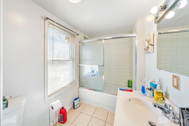 full bathroom featuring tile patterned flooring, sink, combined bath / shower with glass door, and toilet